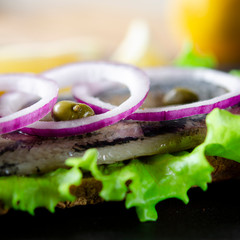 Appetizing smorrebrod with Norwegian herring, lettuce, blue onion, lemon and tomato lies on a...