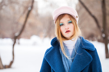 Portrait of a young beautiful blonde girl in a blue coat