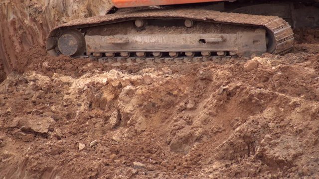 crawler excavator digging the earth with a bucket at a construction site, close-up, industry.