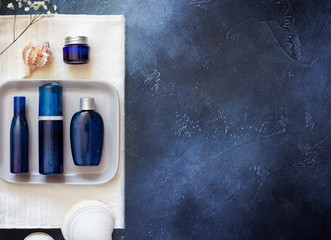 Cosmetic Spa mockup. Blue cosmetic bottles on a white towel with shells on a blue background. Beauty salon, table with creams and towels, top view, copy space