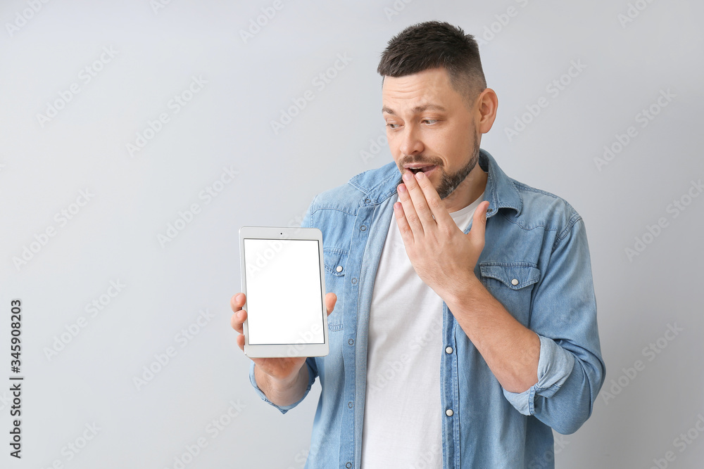 Aufkleber surprised man with tablet computer on grey background