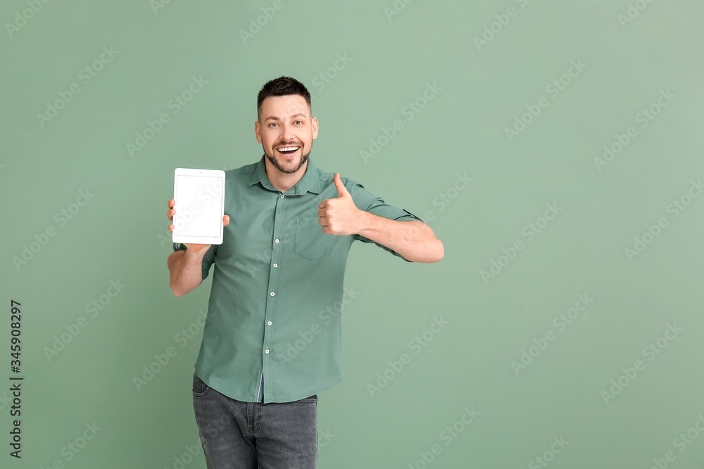 Poster handsome man with tablet computer showing thumb-up on color background