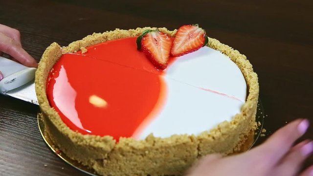 confectioner by knife takes away one half of cheesecake with shortbread border