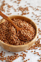 Raw dry buckwheat grain  in a bowl with a spoon