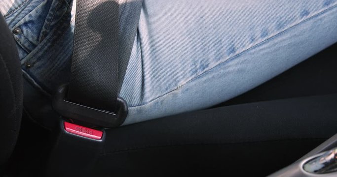 female hand fastening car safety seat belt while sitting inside of vehicle before driving