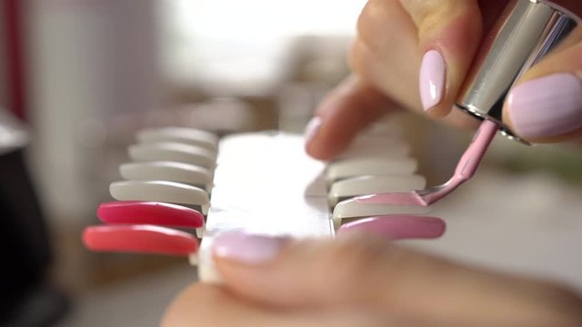 Manicure nail templates painting. Colorful nail lacquer. Woman is coloring artificial false nails with pink lacquer and putting them into a uv lamp nail hardener. 