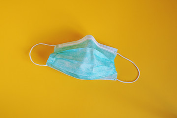 medical or surgical mask - used disposable protective face mask on yellow background