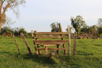 A stile in a field in the countryside crossing over a field with a fence. 