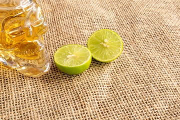 bottle of typical Brazilian drink in the shape of a skull, cachaça, in jute fabric with cut lemon