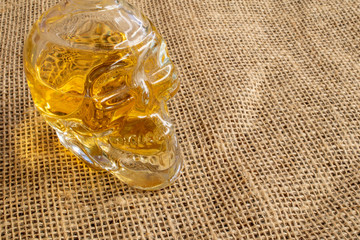 bottle of typical Brazilian drink in the shape of skull, cachaça, in jute fabric