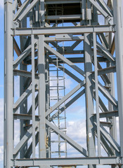 Element of a metal tower. Staircase with safety guard. Robust construction for walking up. View from the side. Concept of a tower crane, a high-rise structure.