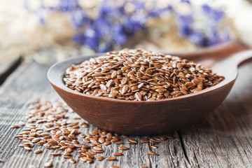 Flax seeds in a spoon on a wooden table.