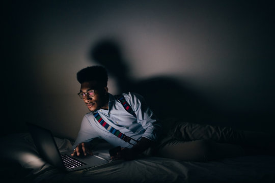 Young Handsome Man Awake At Night Lying Bed Using Computer - Business, Deadline, Overtime Concept