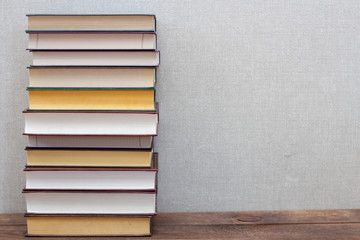 A stack of books on a wooden shelf and a gray background. Free copy space for text