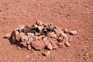 Campfire in the desert. Charred stones are stacked in a circle. Brown color with a red tinge of rock and surface. Concept of a bonfire in a remote area, a journey along Mars.