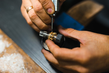 Master goldsmith while working on jewelry on the of work table.