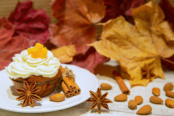 Sweet cupcake muffins with cinnamon and nuts on autumn leaves background. Fall dessert.