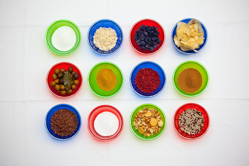 Colorful bowls with a different seasoning, spices and snacks on the white background