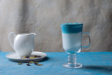 Dalgona Matcha Blue Latte, cream matcha in a glass cup on a blue background.