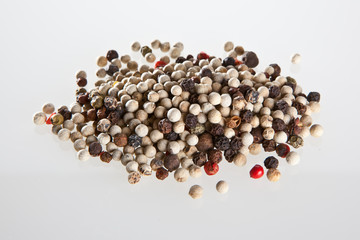 White and black peppercorns on the white background