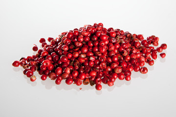 Mountain of pink and red peppercorns on the white background with reflects