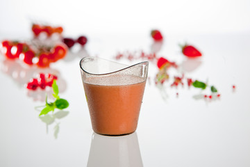 Traditional spanish tomato cold soup in the plastic glass on the white background with decoration