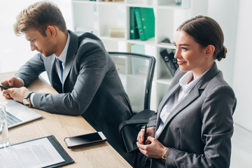 Selective focus of smiling recruiter sitting at table near colleague in office