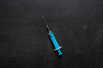 medical syringe on a black chalk board background. empty place. Medicine.