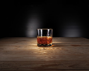 Glass of whiskey with ice cubes on a wooden table . Alcoholism concept . Addicting to alcoholic drink.