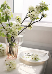 
spring flowers on the table. branches of a blossoming pear in a vase on a table by the window. interior details