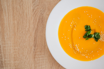 Healthy food, Diet, Detox, Clean Eating or Vegetarian concept. bright delicious pumpkin soup puree, poured with oil and sprinkled with sesame seeds. stands on a wooden table