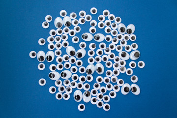 googly toy eyes on classic blue background. concept of personal data security, surveillance, espionage. top view