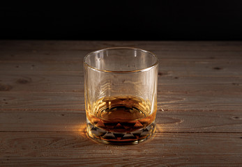 Glass of whiskey with ice cubes on a wooden table . Alcoholism concept . Addicting to alcoholic drink.