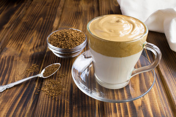 Dalgona coffee in the glass cup in the brown wooden  background. Closeup.