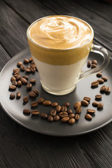 Dalgona coffee in the glass cup in the black wooden  background. Location vertical.