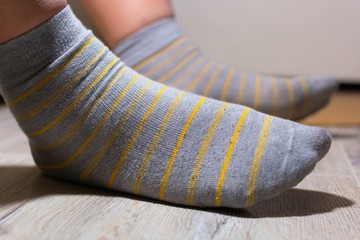 Men's gray socks with yellow stripes. Legs in socks, one leg in the air. Low start.