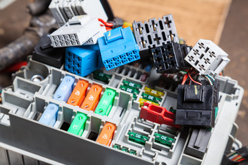 Automotive fuses on the panel with connectors and multi-colored marked housings - protective device with AC sensors. Diagnostics and repair of the mains in case of an error in a car service.