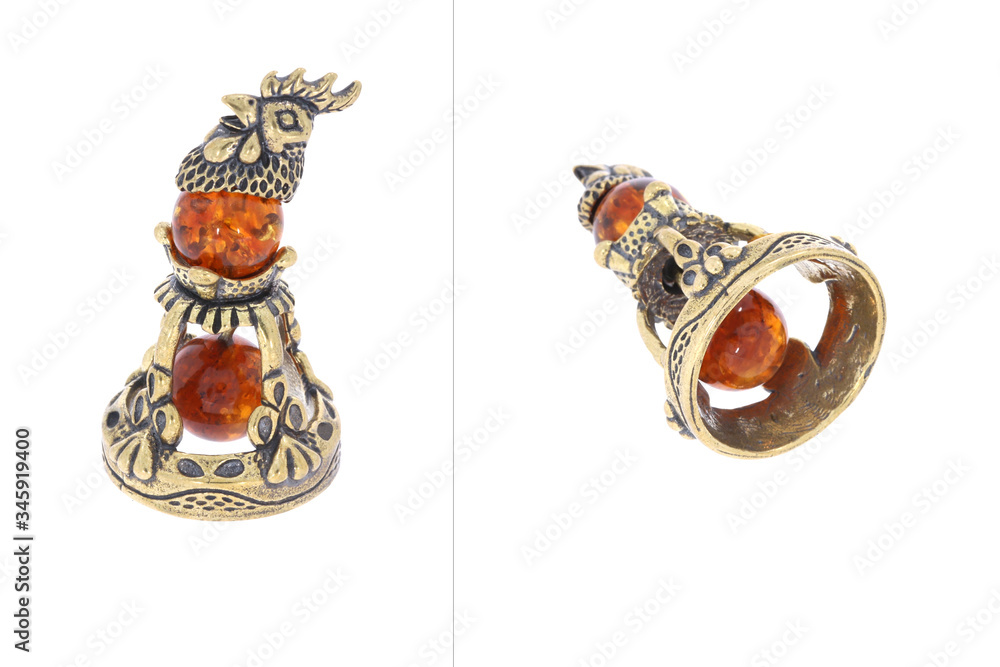 Wall mural Amber souvenir. A miniature metal bell with an amber element. Background is dark brown or white (isolated image).