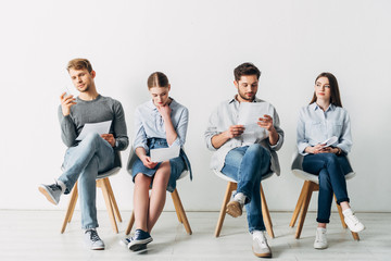 Group of young people with resume waiting for job interview in office