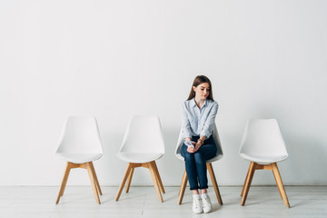 Beautiful employee with resume sitting on chair in office