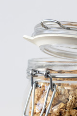 Mason jar filled with granola and open lid on white background