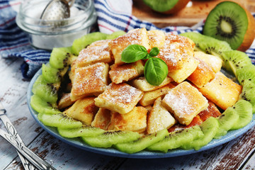 Austrian dessert Kaiserschmarrn served with sugar powder and kiwi fruit