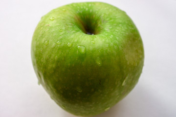 Green apple with drops of water on a white background