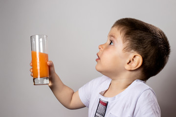 Little boy holds a glass of fruit juice. Vitamins for children, healthy baby food.