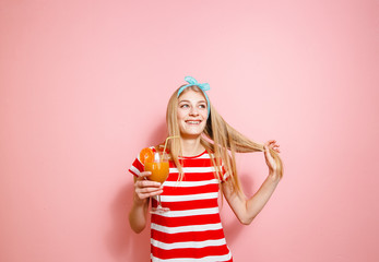 Happy blonde who drinks lemonade and smiles pleasantly on pink background.