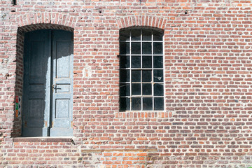 Fototapeta na wymiar Brick facade with old door and tiled window