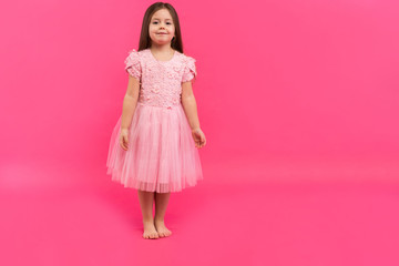 Cute little girl dreams of becoming a ballerina. Little Dancing Girl. Studio Shoot Over Pink Background