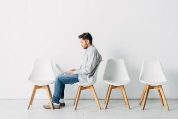 Side view of candidate using laptop on chair in office