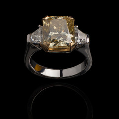 Jewelry, golden ring with a diamond on a black background, reflection from a shiny surface