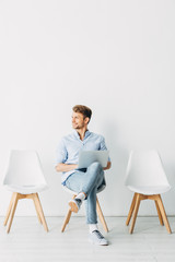 Fototapeta premium Smiling employee with laptop looking away in office